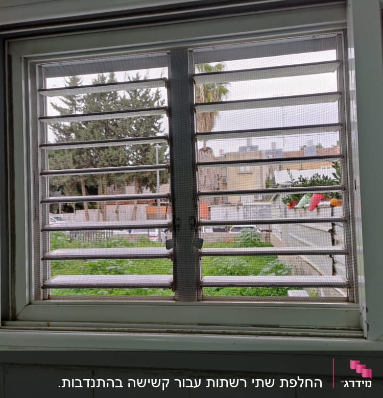 תריסי אלומיניום בחלון עם נוף חיצוני